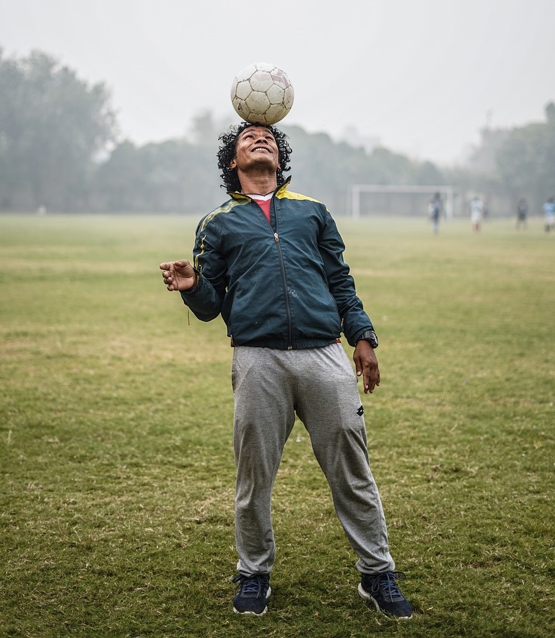 fussballspieler balanciert ball auf stirn