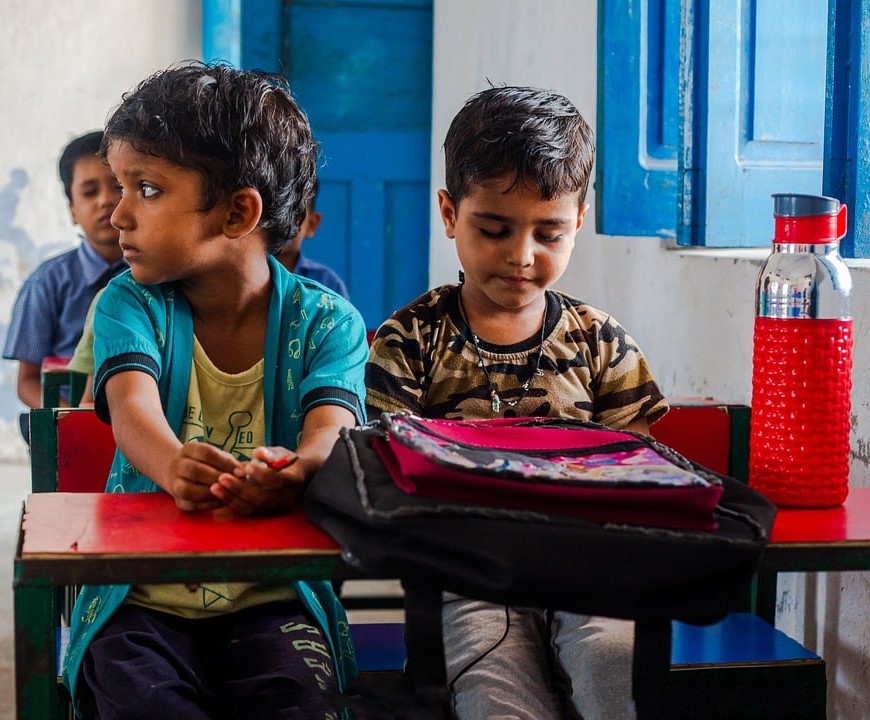 indische Schulkinder mit Trinkflasche auf dem Pult