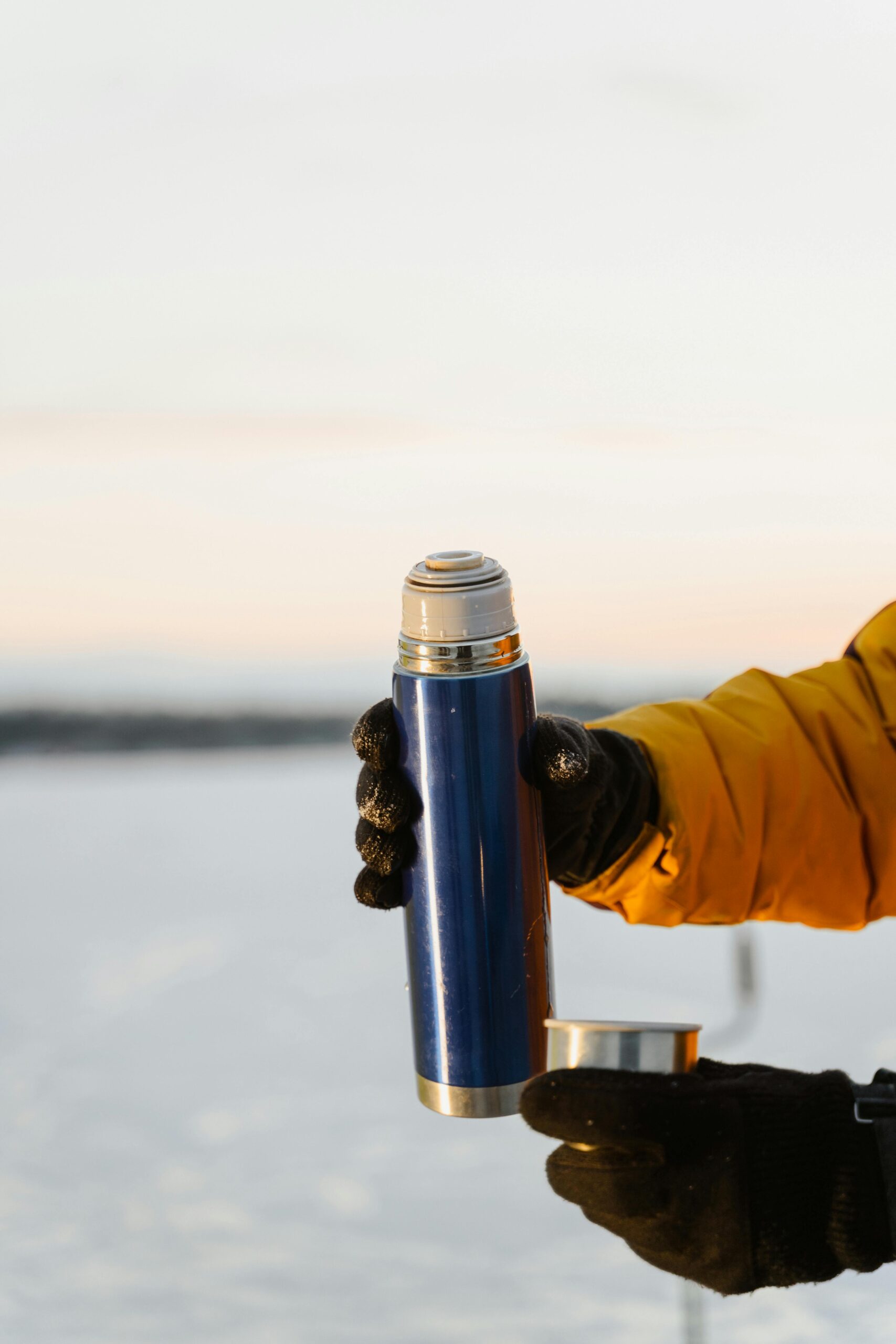 Hand mit Handschuh hält Thermosflasche