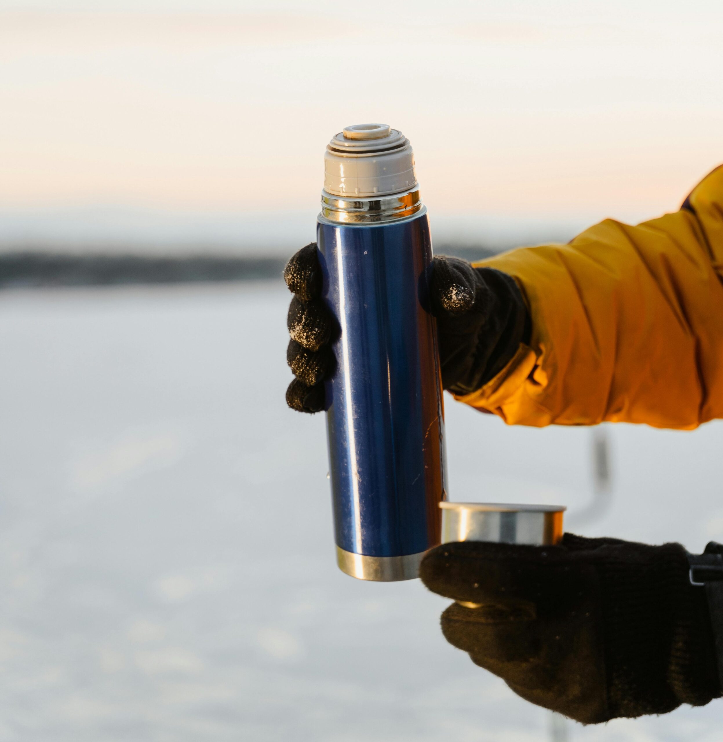 Hand mit Handschuh hält Thermosflasche