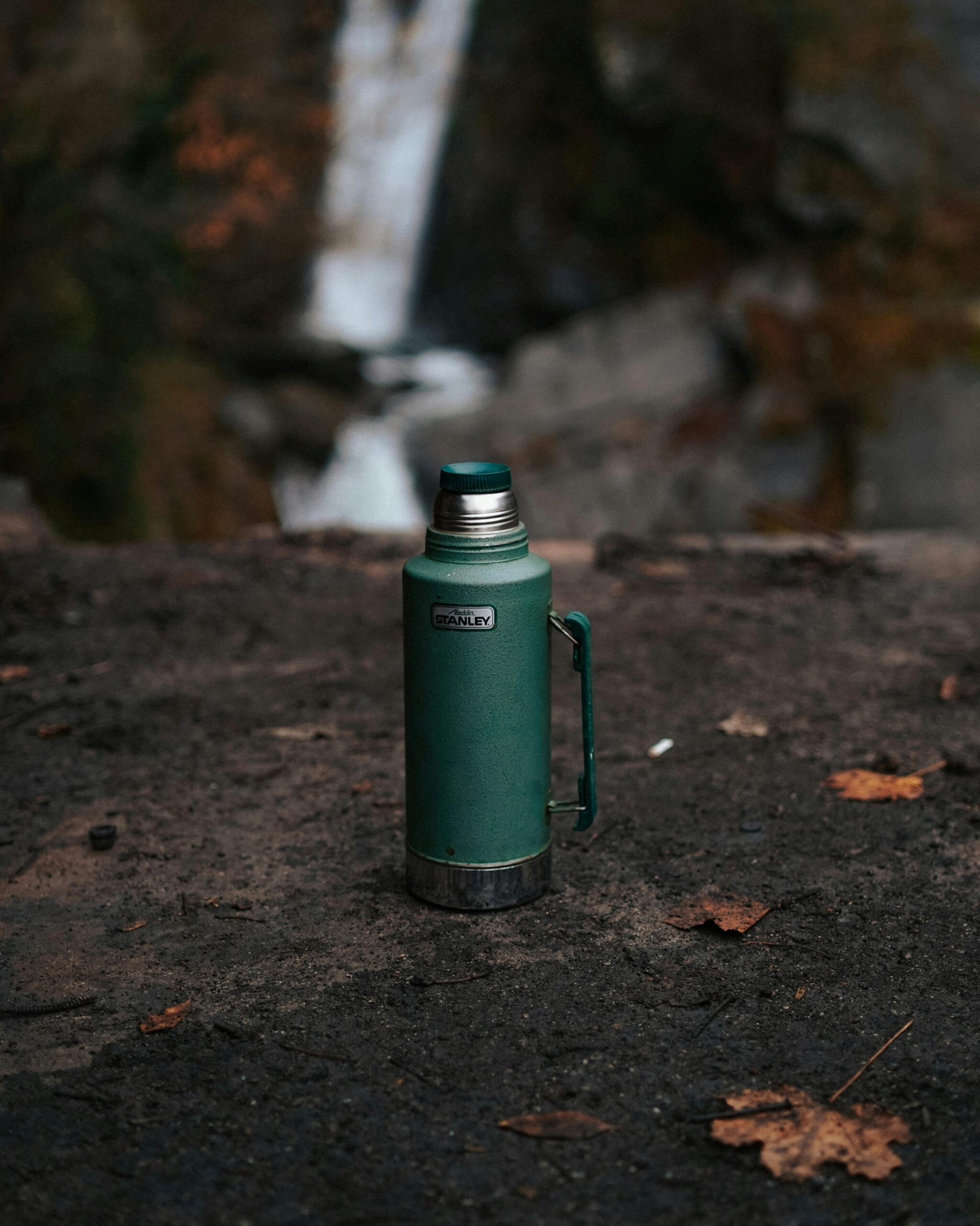 Trinkflasche steht auf Stein mit Wasserfall im Hintergrund