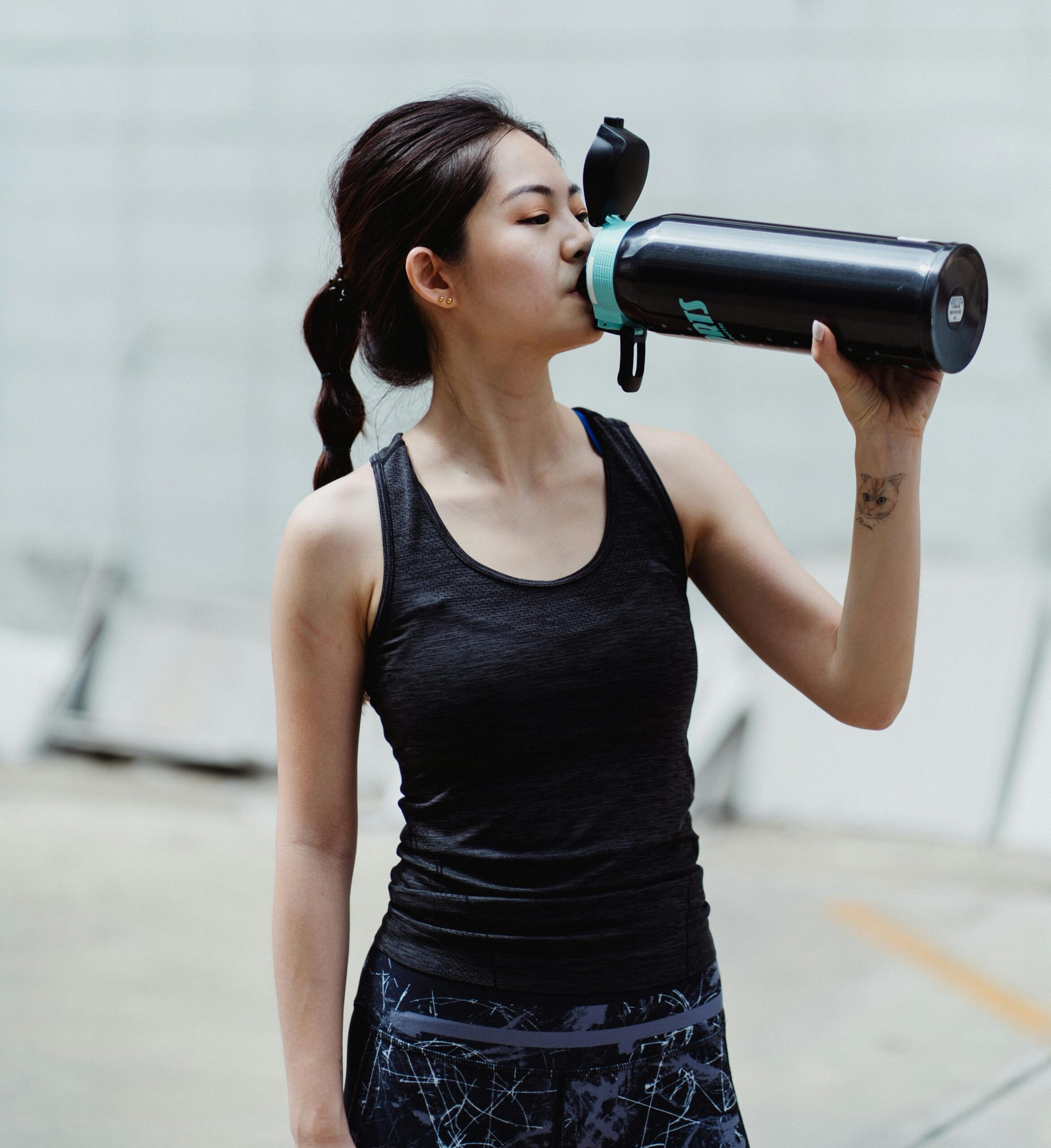 Frau beim Fitness-Training trinkt aus Trinkflasche