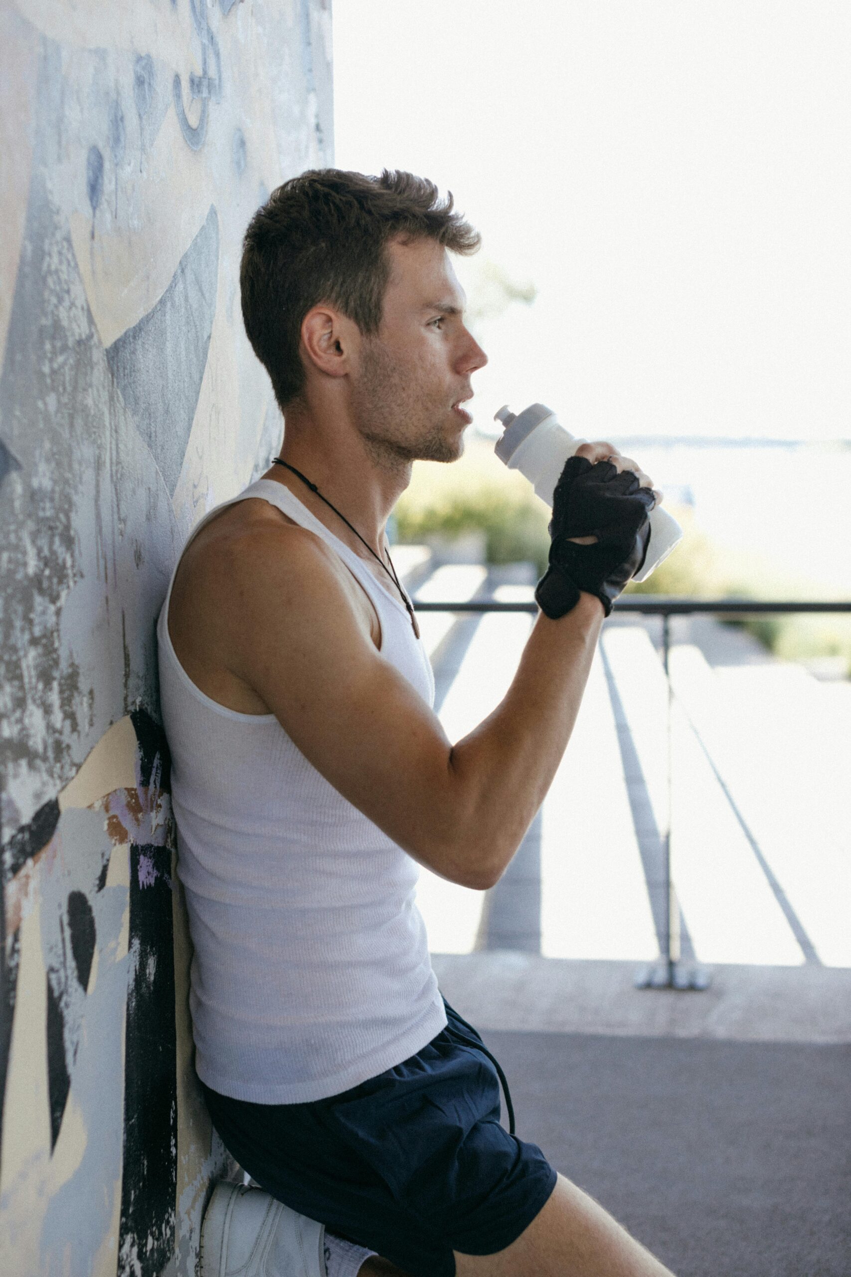 Mann beim Fitnesstraining trinkt aus Kunststoffflasche