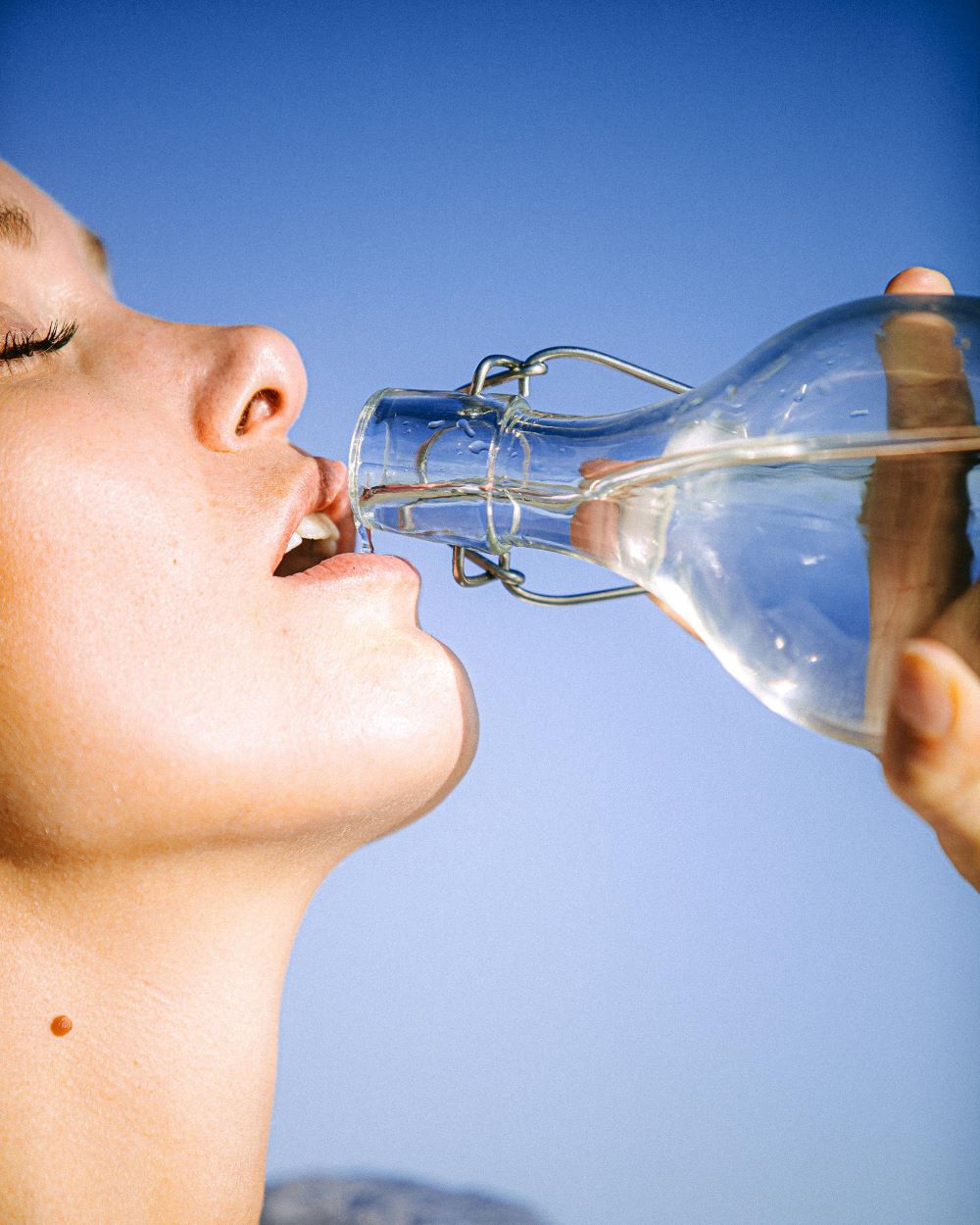 mehr Wasser trinken. Frau trinkt aus Glasflasche