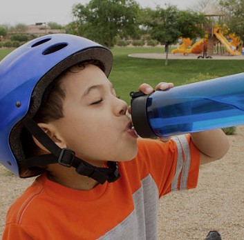 Junge mit Fahrradhelm trinkt aus Flasche